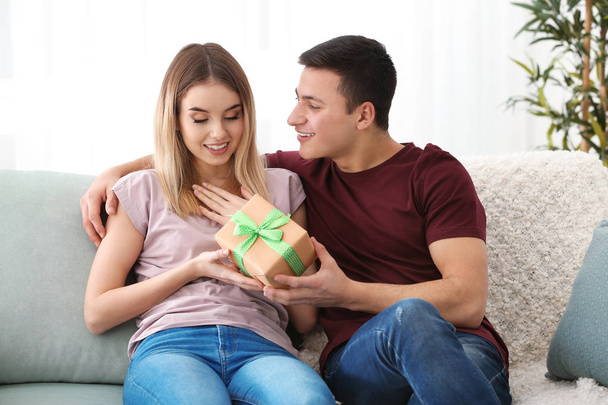Young man giving present to his beloved girlfriend at home - Photo, Image