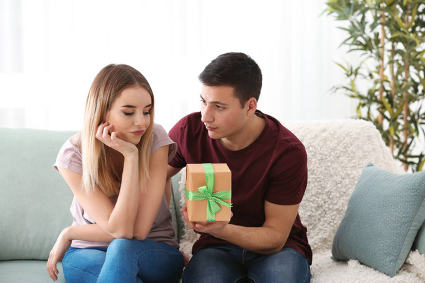 Young man giving present to his beloved girlfriend at home - Foto, afbeelding
