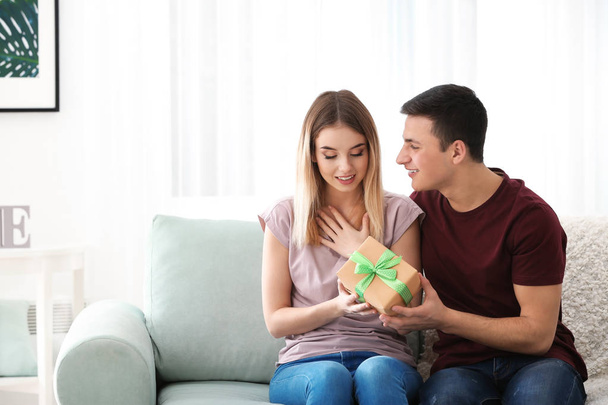 Young man giving present to his beloved girlfriend at home - Photo, Image