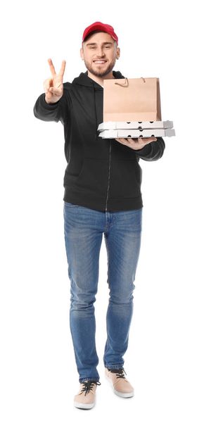 Νεαρός άνδρας με κουτιά πίτσας από χαρτόνι και χαρτί τσάντα σε λευκό φόντο. Υπηρεσία παράδοσης τροφίμων - Φωτογραφία, εικόνα