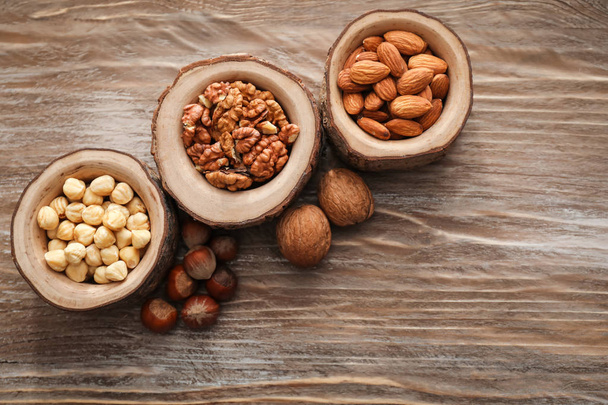Bowls with various tasty nuts on wooden table - Foto, Imagen