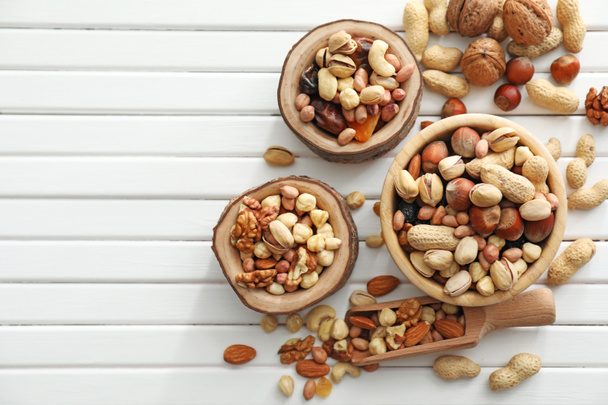 Bowls and scoop with various tasty nuts on wooden table - Photo, Image
