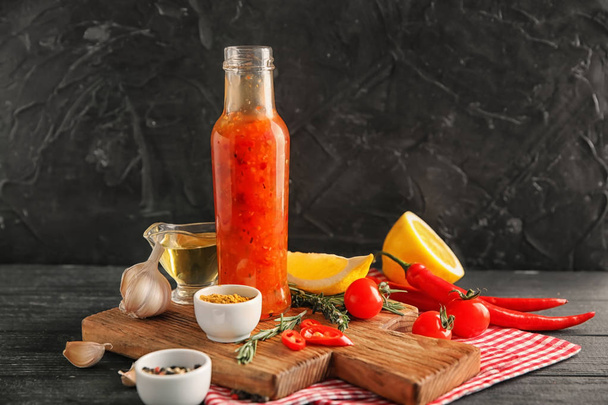 Μπουκάλι με νόστιμη σάλτσα, λαχανικά και καρυκεύματα στο τραπέζι - Φωτογραφία, εικόνα