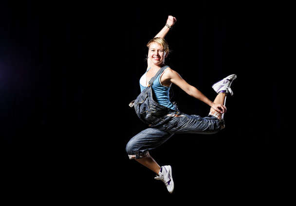 Stylish hip-hop female dancer performs on the stage on black background - Foto, immagini