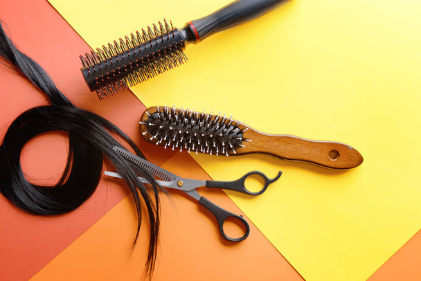 Flat lay composition with hairdresser's tools and strand of black hair on color background - Fotó, kép