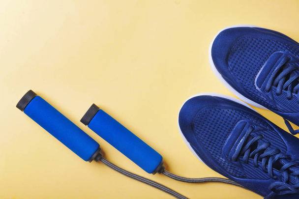 Composición plana con zapatillas y cuerda de salto sobre fondo de color. Entrenamiento en el gimnasio
 - Foto, imagen