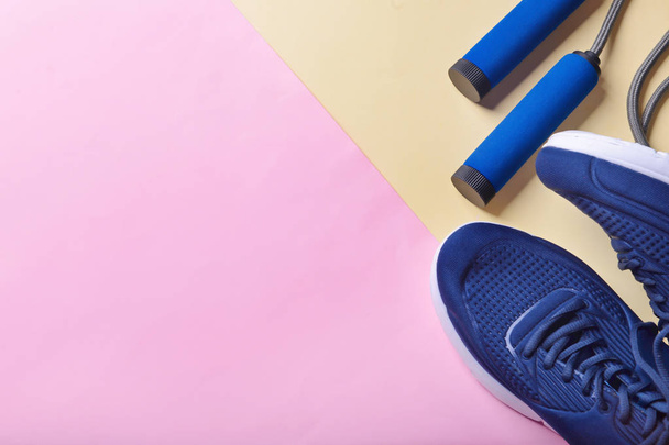 Flat lay composition with sneakers and jumping rope on color background. Gym workout - Photo, Image