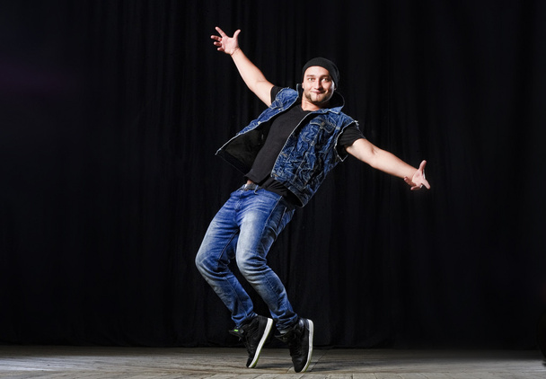 stylischer Hip-Hop-Tänzer tritt auf der Bühne auf schwarzem Hintergrund auf - Foto, Bild
