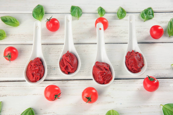 Deliziosa salsa rossa in cucchiai di ceramica con pomodorini ciliegini sul tavolo
 - Foto, immagini