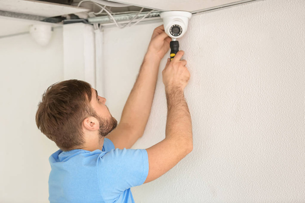 Electrician installing security camera indoors - 写真・画像