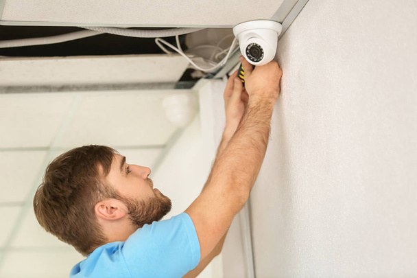 Electrician installing security camera indoors - Фото, изображение