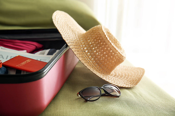 Open suitcase with packed things on bed - Fotoğraf, Görsel