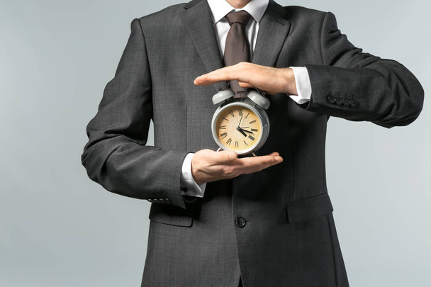 Man holding clock on grey background. Time management concept - Photo, Image