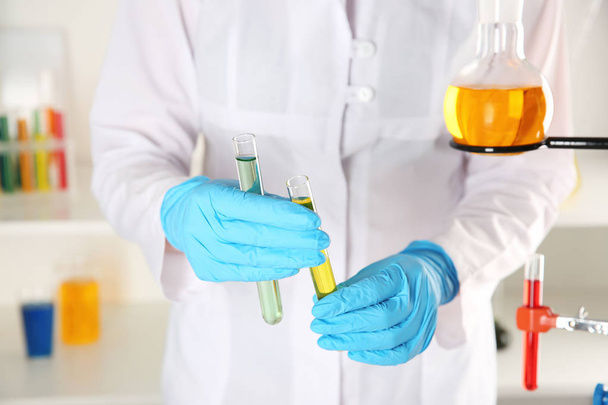Laboratorium assistent holding reageerbuisjes met kleurrijke vloeistoffen, close-up - Foto, afbeelding