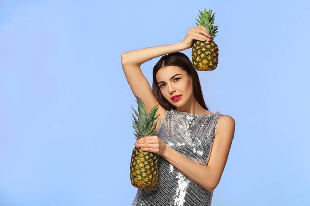 Attractive young woman with two pineapples on color background - Foto, Bild