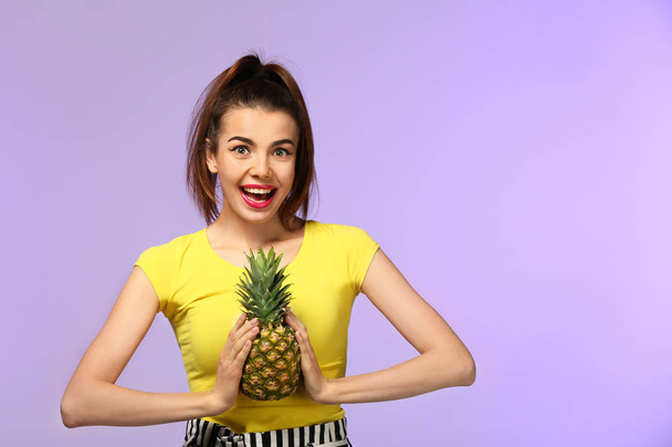 Emotional young woman with pineapple on color background - Photo, Image