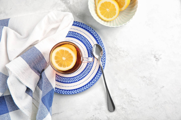 Coupe en verre de thé aromatique avec citron sur l'assiette
 - Photo, image