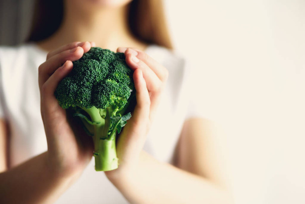 Woman in white T-shirt holding broccoli in hands. Copy space. Healthy clean detox eating concept. Vegetarian, vegan, raw concept. Banner - Photo, image