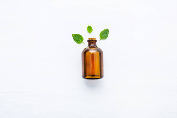 Huile essentielle de menthe naturelle dans une bouteille en verre avec feuilles de menthe fraîche sur fond blanc
. - Photo, image