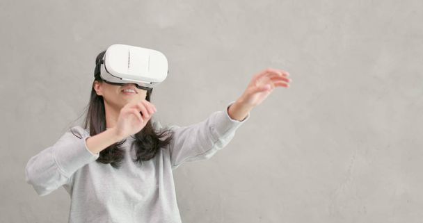Woman playing VR device over gray background  - Foto, Imagem