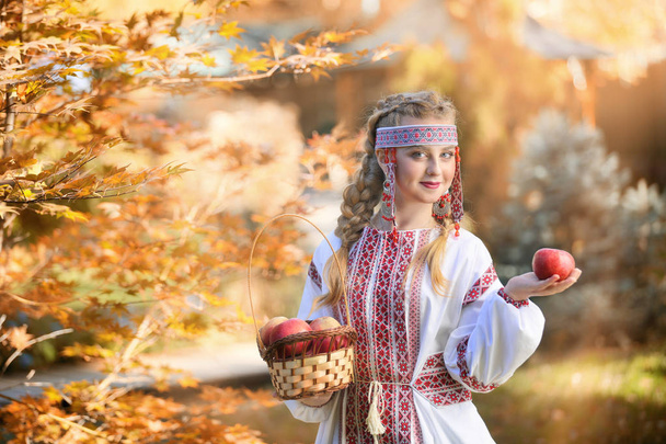 Chica en traje popular ruso sosteniendo manzanas
  - Foto, Imagen