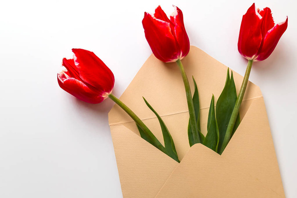 a bouquet of three red tulips lies in an envelope - Foto, Imagen