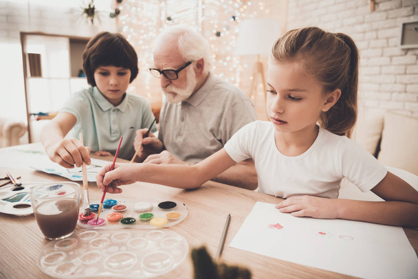 Grandfather, grandson and granddaughter drawing at home - Фото, изображение