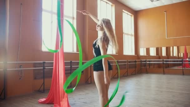 Rhythmic gymnastics - young woman training a gymnastics exercise with a ribbon, slow-motion - Materiał filmowy, wideo