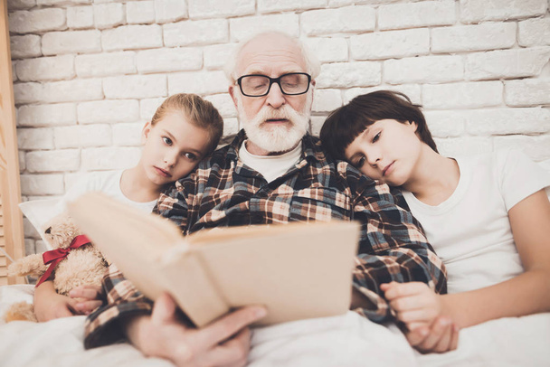 Grandpa reading book with children at home - Foto, Bild