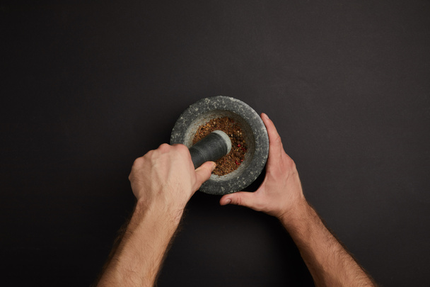 partial view of man with mortar and pestle on black surface - Photo, Image