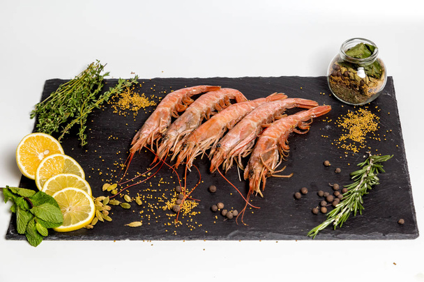 shrimp langoustine lie on a black plate - Фото, изображение