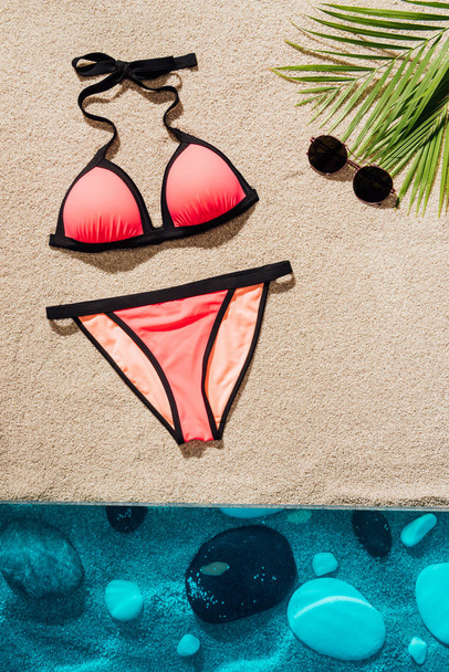 top view of stylish pink bikini with sunglasses on sandy beach - Zdjęcie, obraz