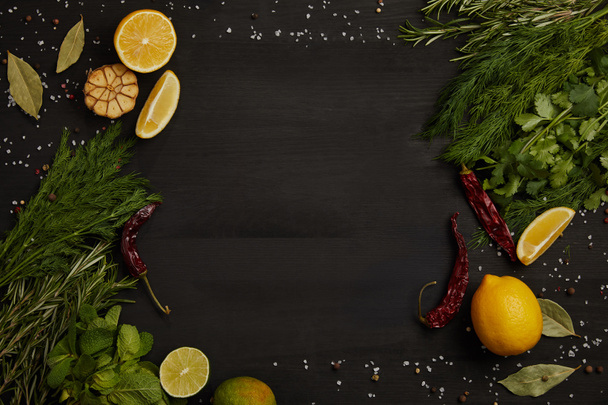 flat lay with citrus fruits, chili peppers, bay leaves, spices, rosemary and parsley on black surface - Foto, Imagem