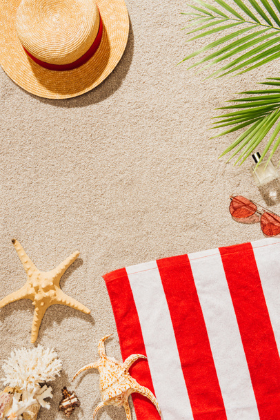vista superior de la toalla rayada con sombrero de paja y gafas de sol en la playa de arena
 - Foto, Imagen