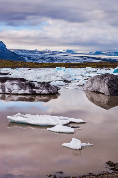 Summer in Iceland. The concept of extreme northern tourism. The picturesque lake with splinters of ice floes formed by thawed snow of grand glacier Vatnajokull  - Photo, image