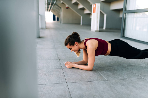 Side portrait of healthy young woman doing plank exercise - Фото, изображение