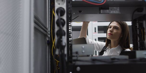 Technician performing maintenance tasks in a server room rack - Zdjęcie, obraz