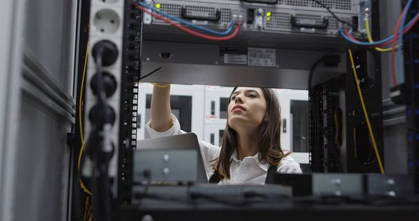 Technician performing maintenance tasks in a server room rack - Fotoğraf, Görsel