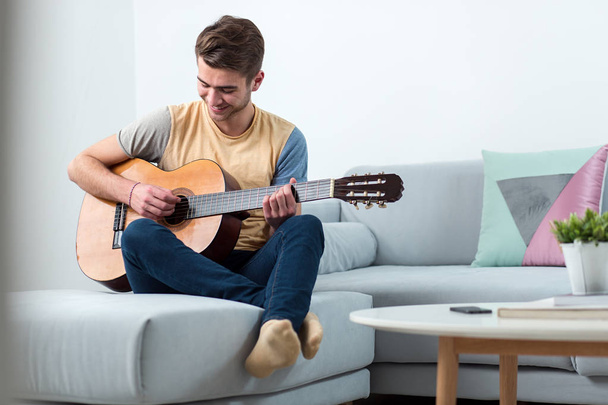 Handsome young player playing a guitar at home. Entertaiment time - Photo, Image