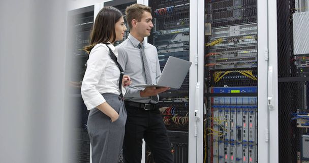 Technicians using laptop while analyzing server in server room - Fotó, kép