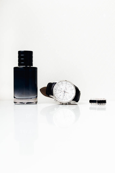 primo piano di profumo, elegante orologio nero e gemelli su sfondo bianco
 - Foto, immagini