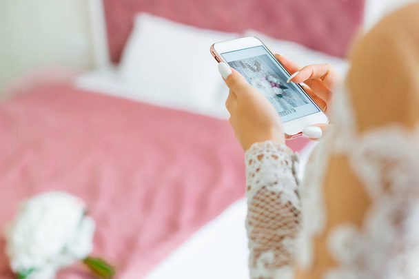 Novia viendo sus fotos en su teléfono en su dormitorio
 - Foto, Imagen