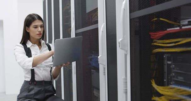 Technician performing maintenance tasks in a server room rack - Fotó, kép