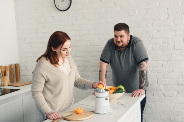 fidanzato sovrappeso e fidanzata preparare succo d'arancia in cucina
 - Foto, immagini