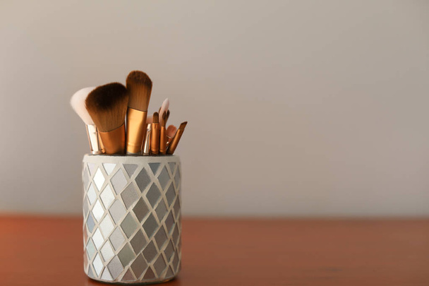 Holder with makeup brushes on table - Foto, afbeelding