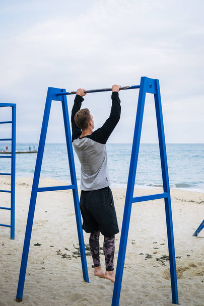 Young man doing parkour tricks on the beach near the sea - Fotoğraf, Görsel