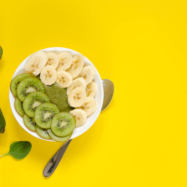 Green smoothie in a white bowl on yellow background - Fotó, kép