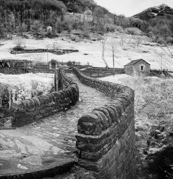 vista ravvicinata in bianco e nero dello storico ponte in pietra di epoca romana in una valle montuosa appartata
 - Foto, immagini