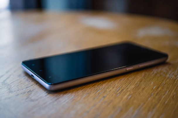 A smartphone rests on a table in a cafe, - Photo, image