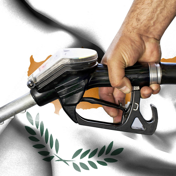 Koncepcja zużycie benzyny - ręka trzyma węża przed flaga - Zdjęcie, obraz